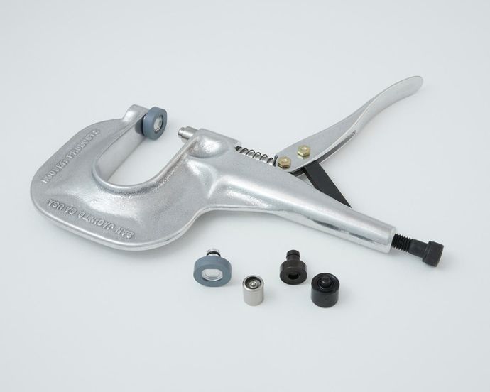 Silver rivet setting tool with several different attachments, on white.