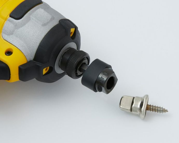 Yellow and black power drill with an attached socket and detached screw head, on a white surface.