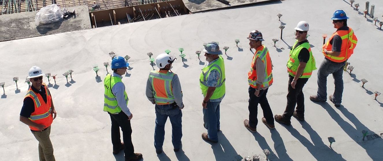 A group of construction workers are standing next to each other on a construction site.