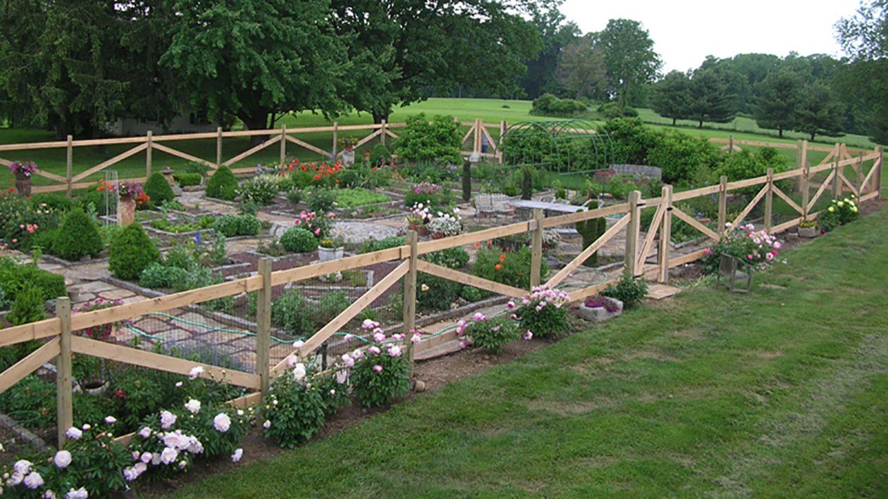 Flower garden beds with wooden trellises and pink blooms in a grassy park