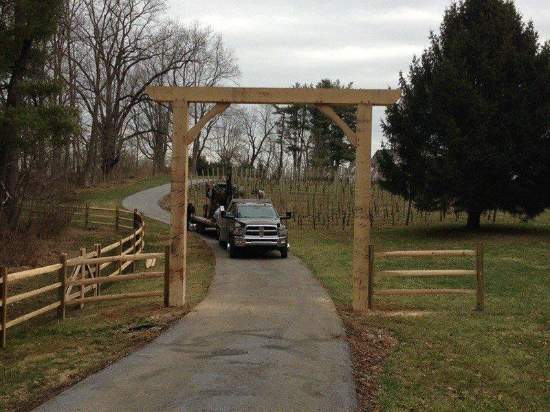 Black SUV driving through a wooden gate on a narrow path in a rural area