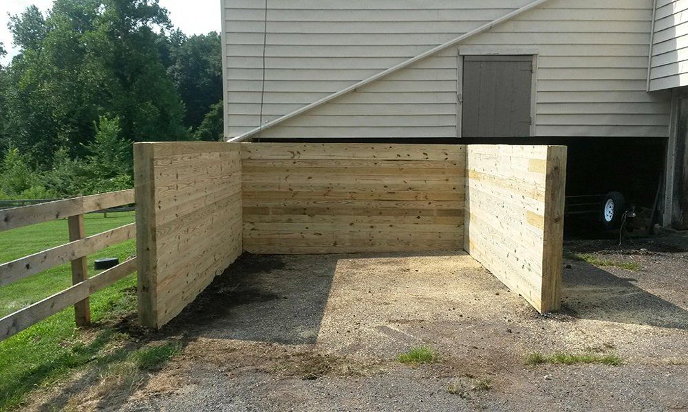 Wooden ramp or enclosure beside a house, with gravel ground and a small door on the right