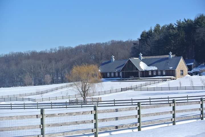 Snowy farm with wooden fences and a house in a winter landscape