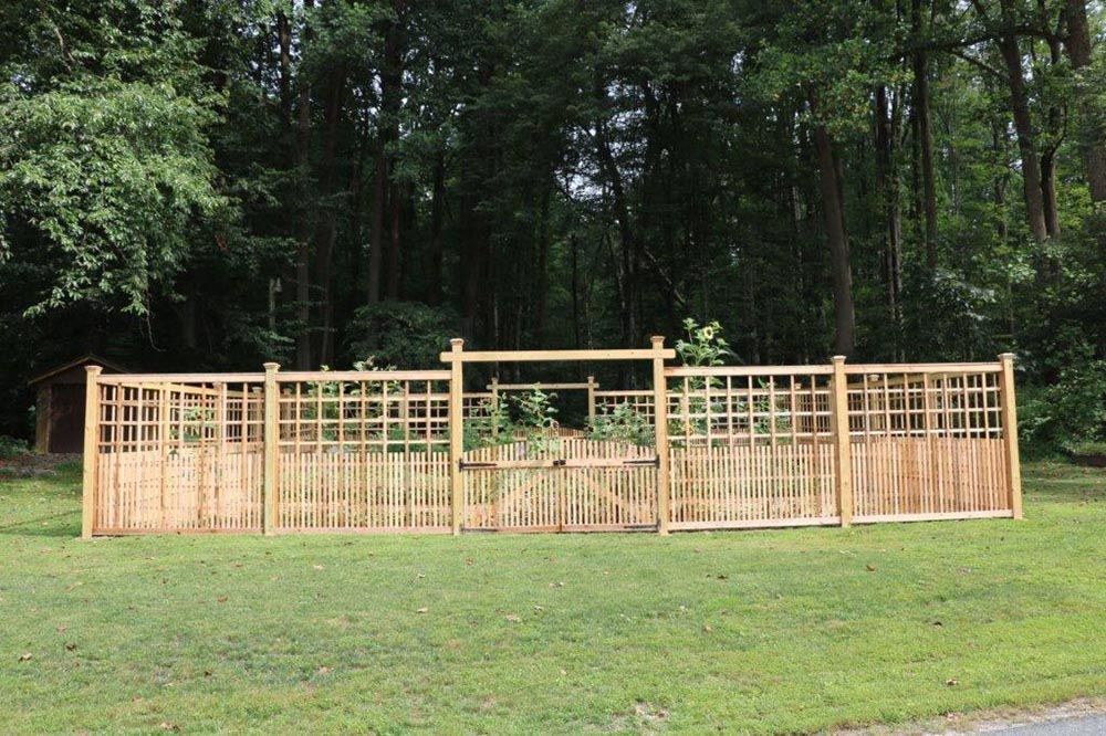 Wooden garden fence panels on a grassy lawn in front of a wooded backdrop