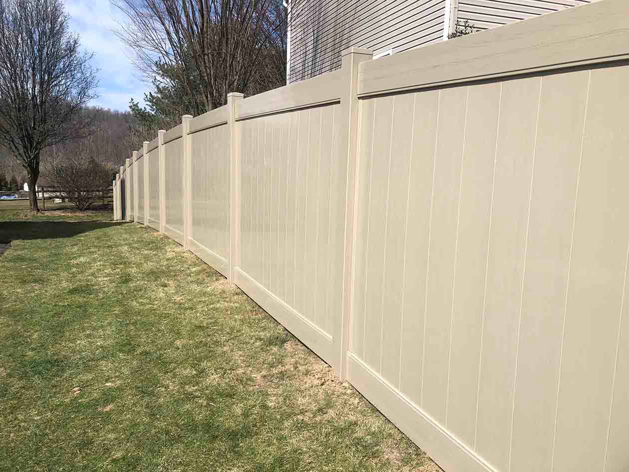Light tan vinyl fence along a grassy yard on a sunny day