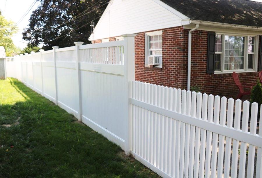 White vinyl fence along a brick house beside a grassy yard
