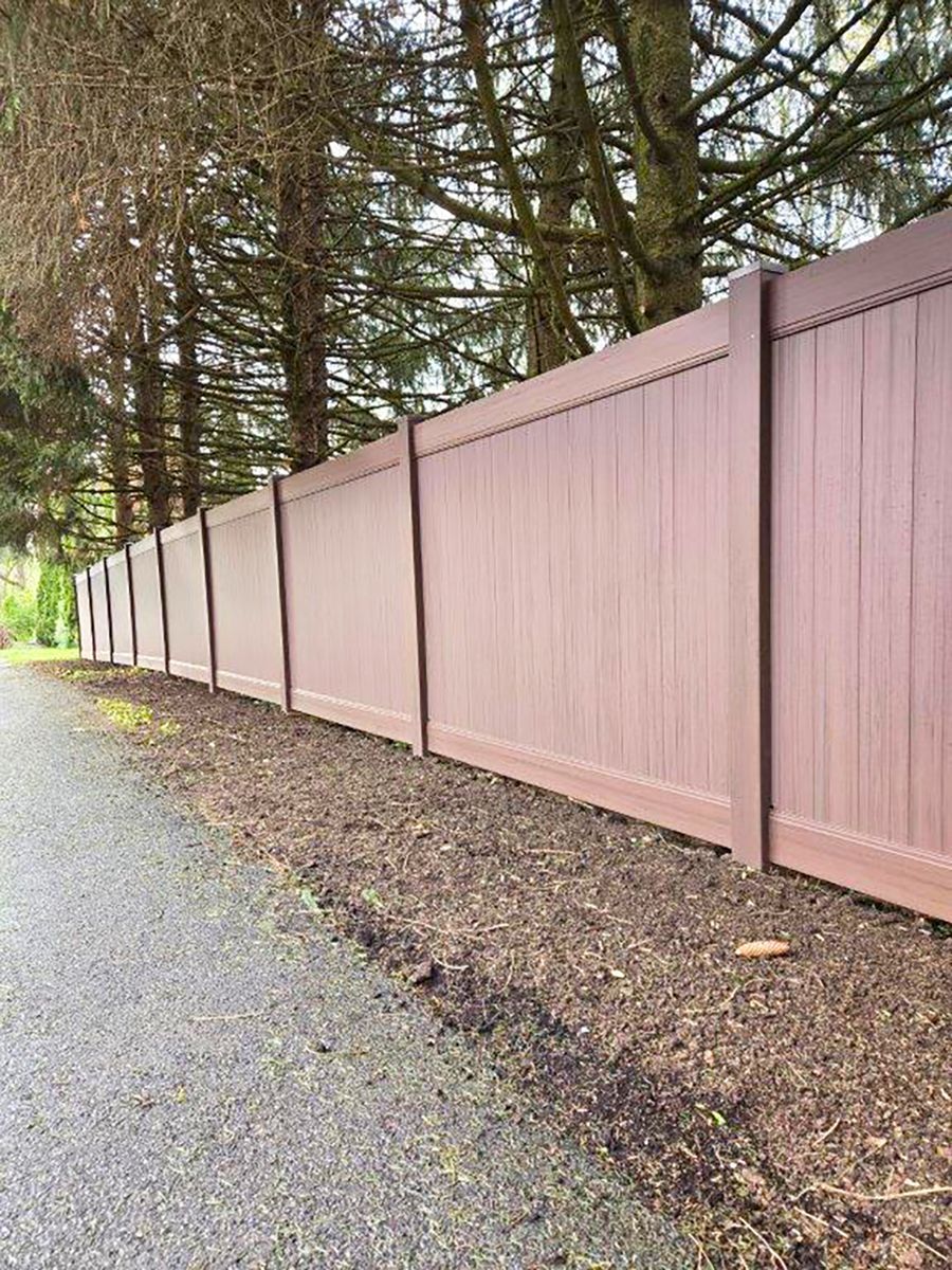 Long pink wooden fence beside a gravel path under trees