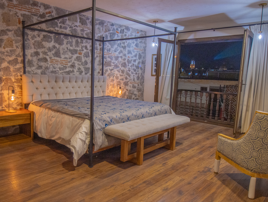 Un dormitorio con una cama con dosel y balcon con vista a Cholula.