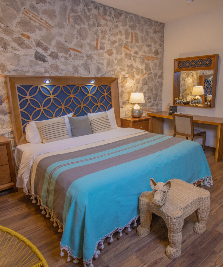 Una habitación de hotel con una cama king size y una pared de piedra con acabados de lujo .