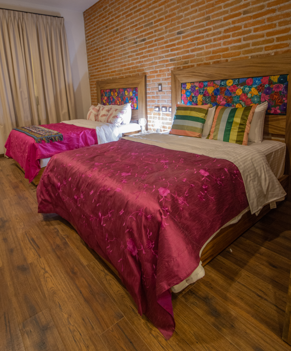 Una habitación de hotel con dos camas y una pared de ladrillos ideal para familias.