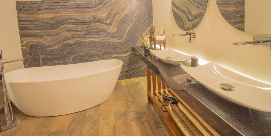 Un baño con dos lavabos y una bañera, ideal para parejas.