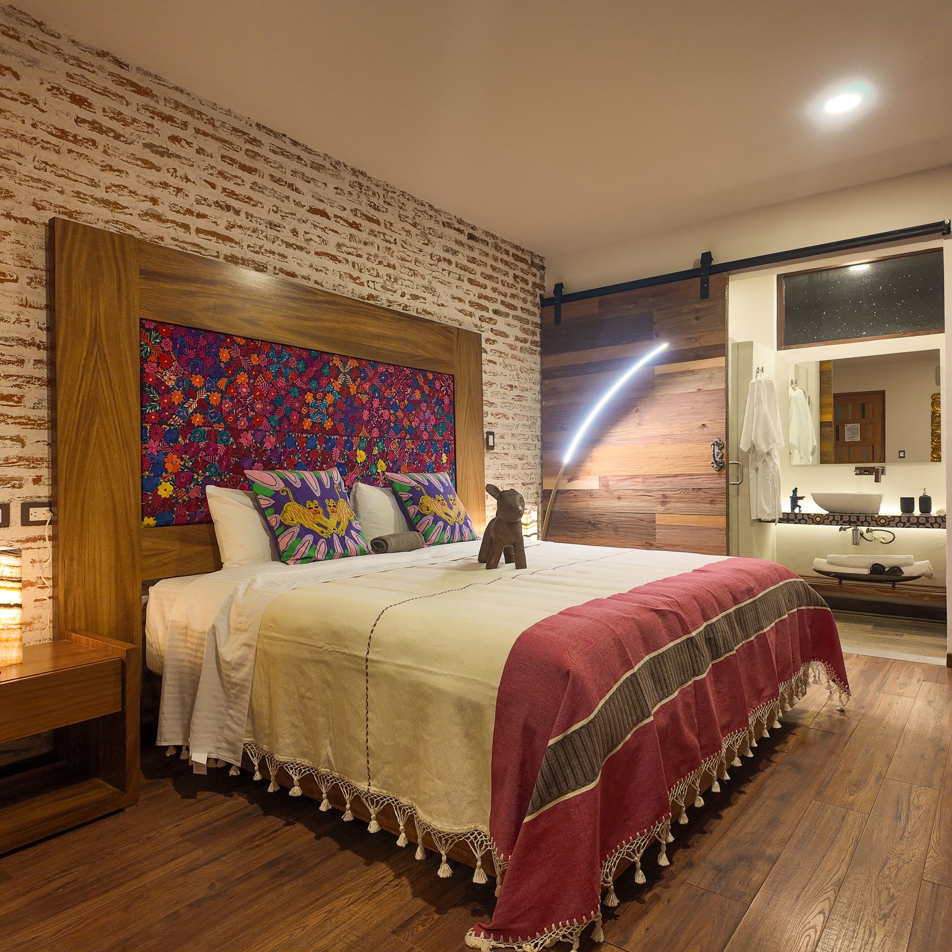 Un dormitorio con una cama grande y una puerta corrediza tipo granero que conecta al baño.