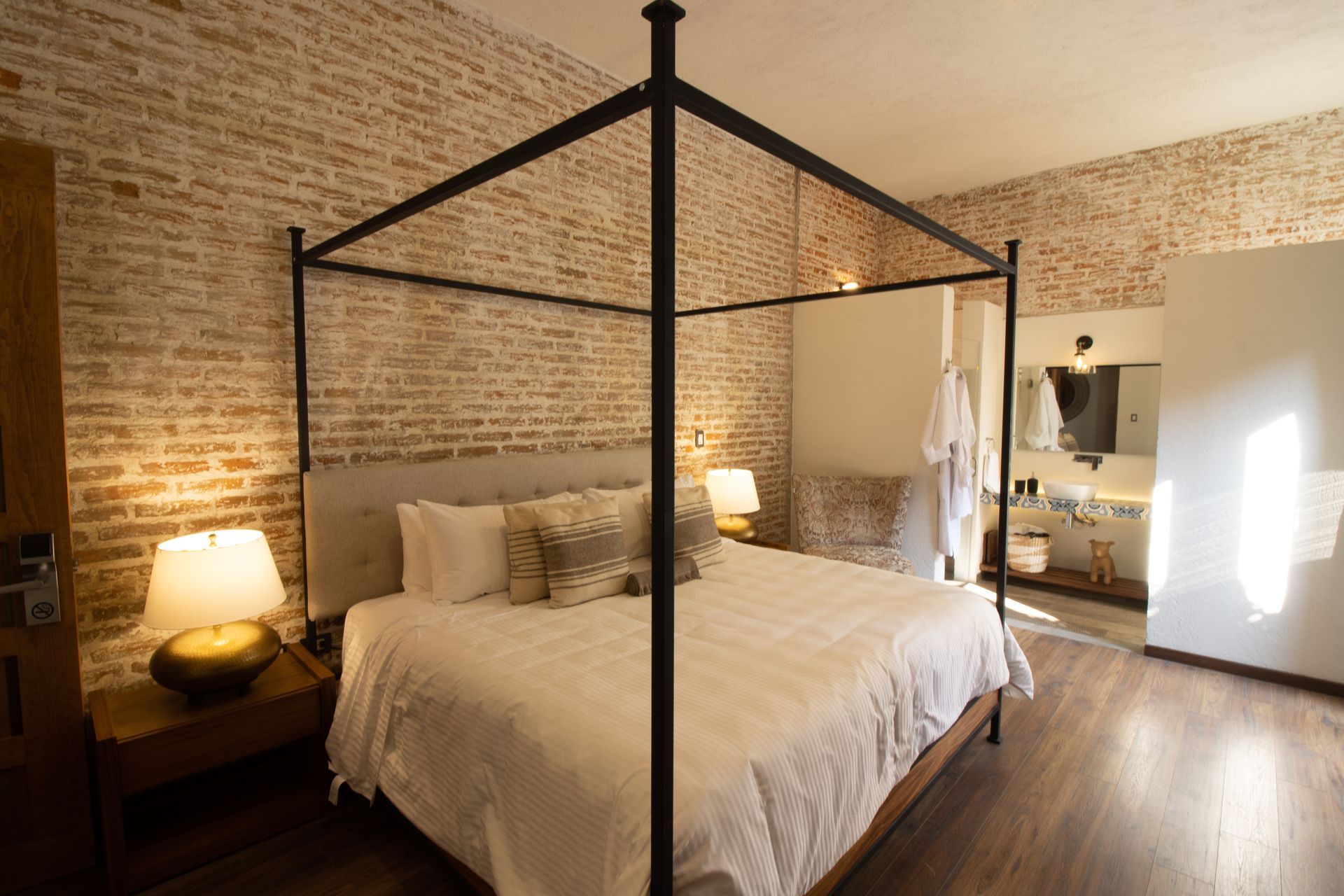 Un dormitorio con una cama con dosel y una pared de ladrillo muy acojedor.