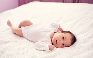 A newborn baby is laying on a bed.