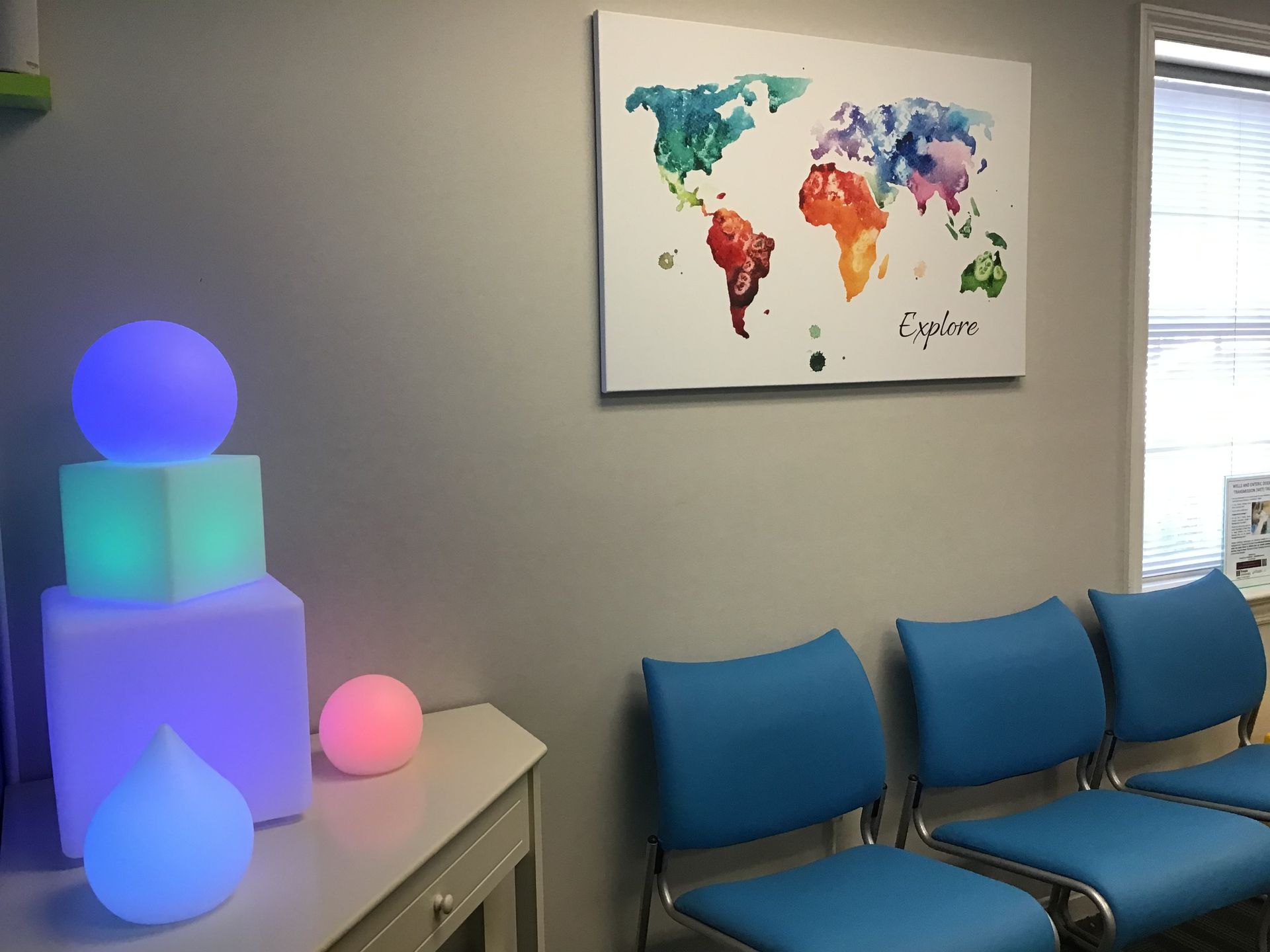 A waiting room with blue chairs and a map of the world on the wall