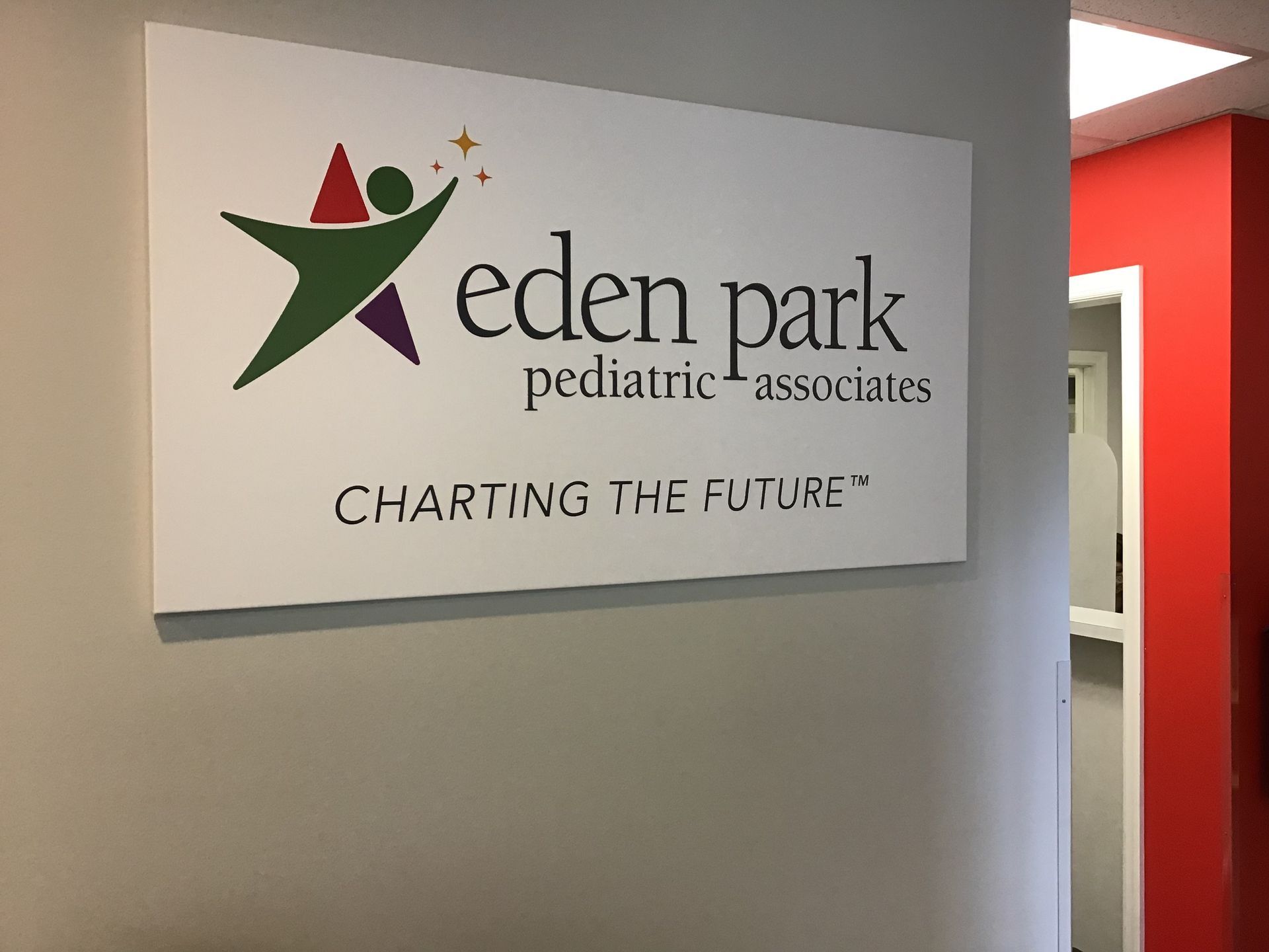 A sign for eden park pediatric associates is on a wall