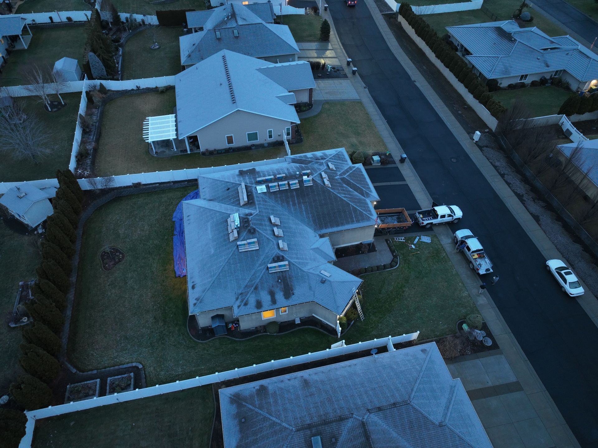 Aerial view of a suburban house with a damaged roof on a residential street.