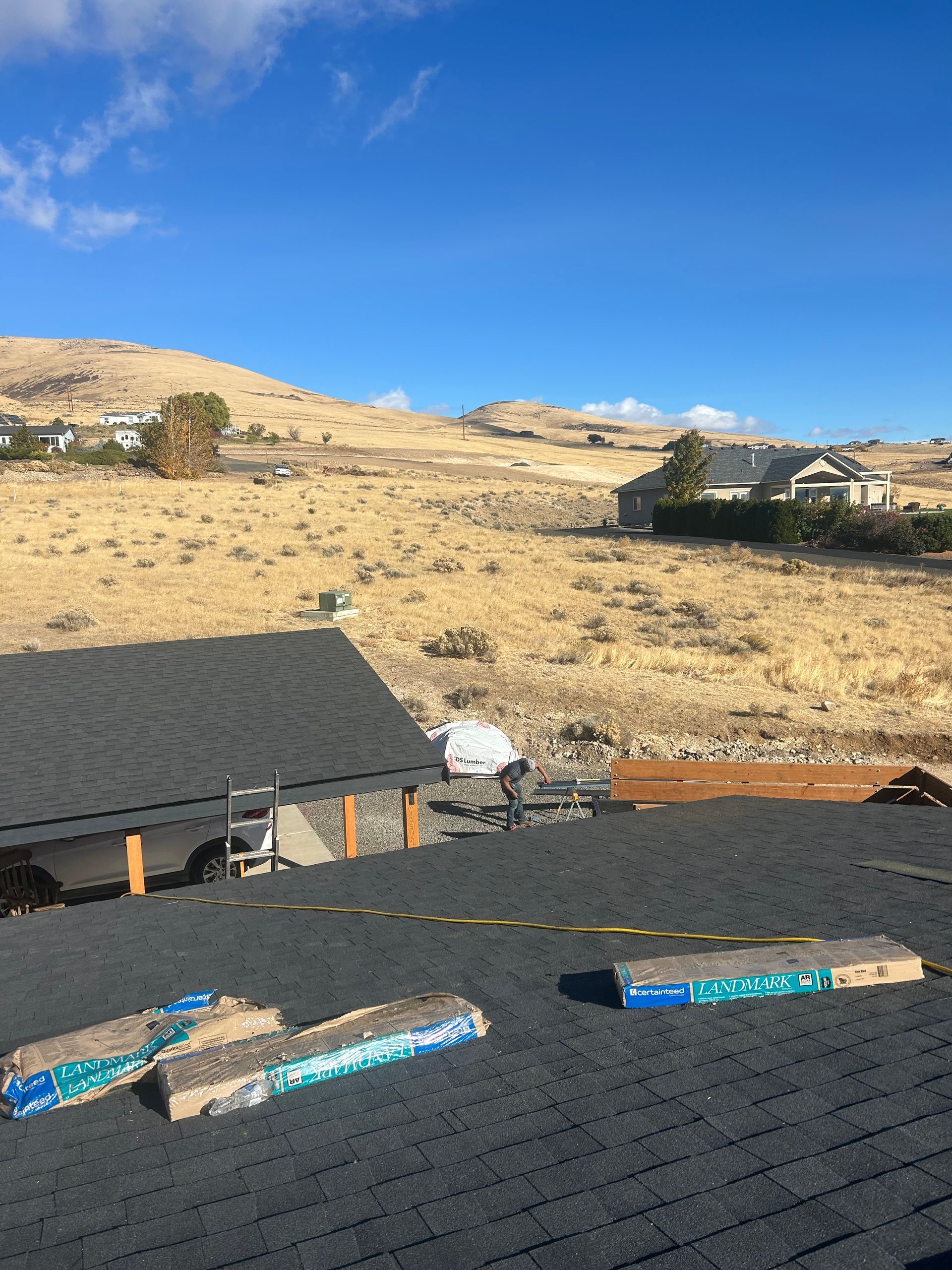 Roof under construction overlooking dry hills beneath a clear blue sky