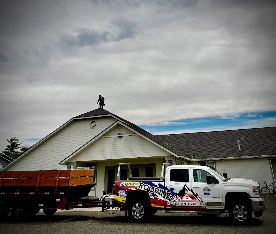 White pickup and flatbed trailer parked in front of a beige house under a cloudy sky