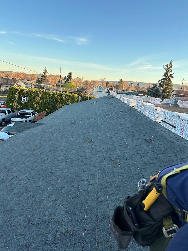 Roofer’s harness on a shingled rooftop with a neighborhood skyline at sunset