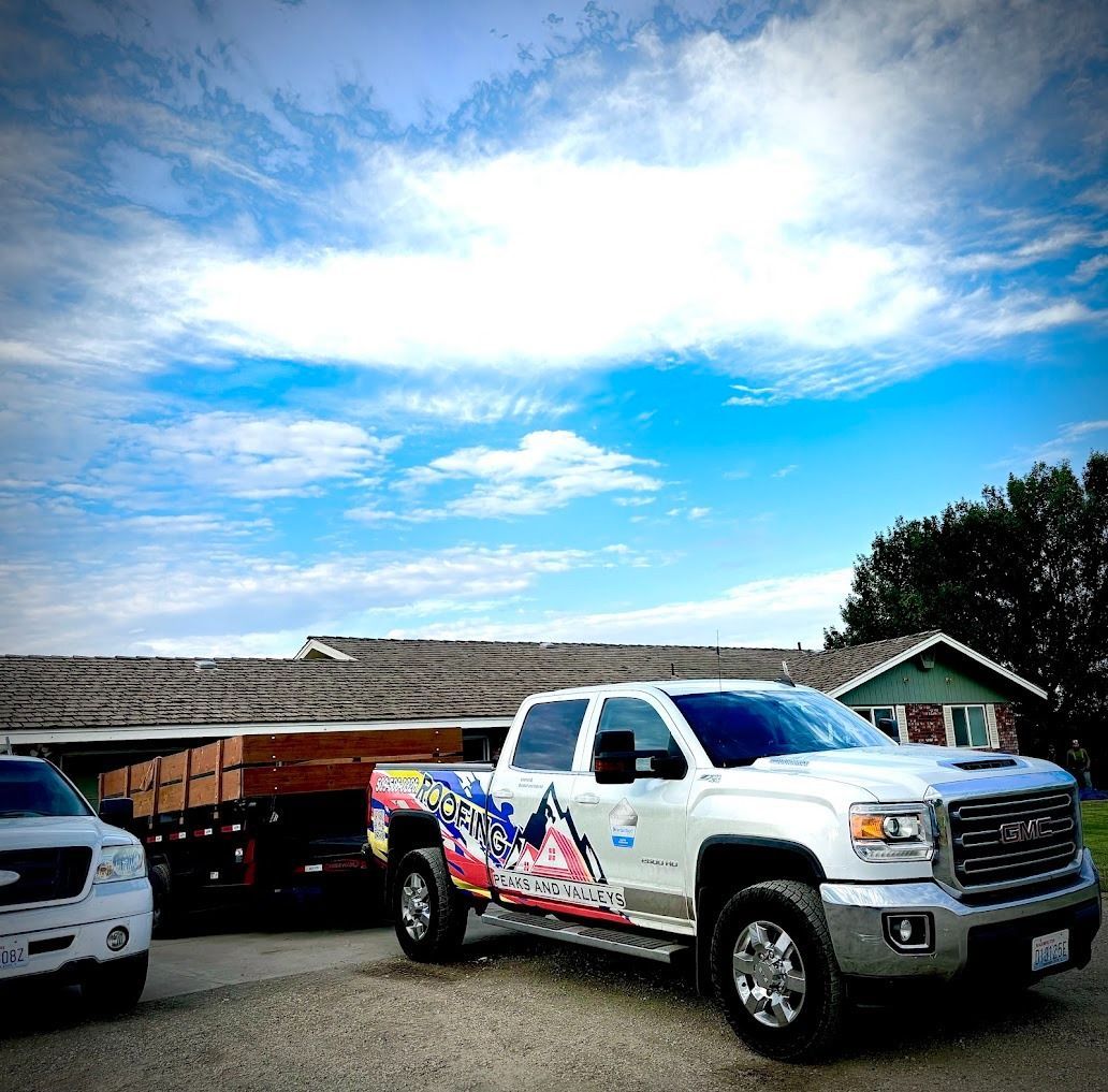 White pickup truck with colorful graphics parked in front of a building under a bright blue sky
