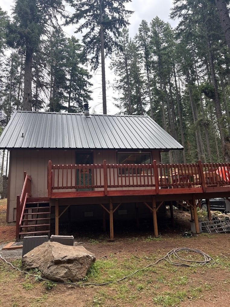 Small cabin with red deck and stairs in a wooded forest clearing