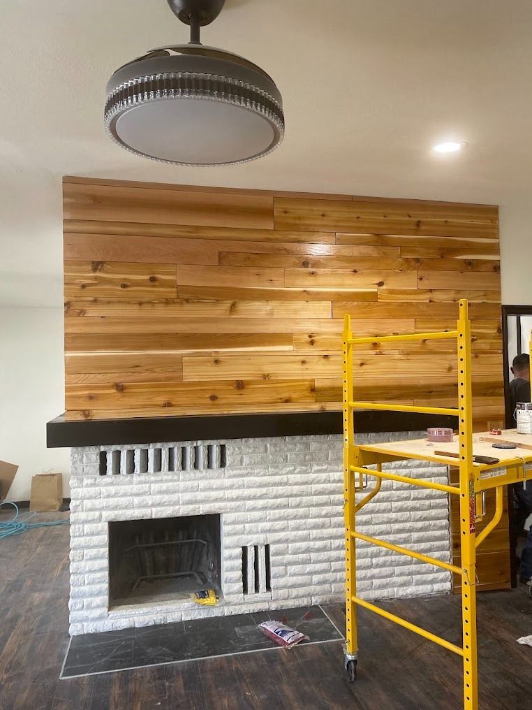 Living room fireplace with white brick, wood accent wall, and yellow scaffolding nearby