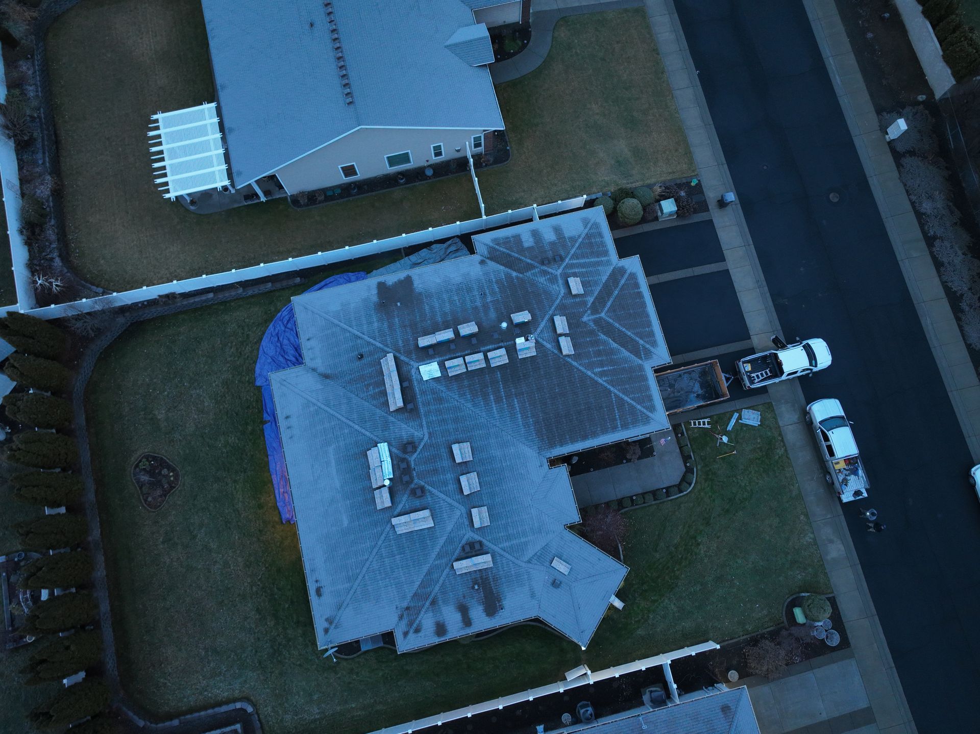 Aerial view of a house with a gray roof, driveway, and yard in a residential neighborhood.