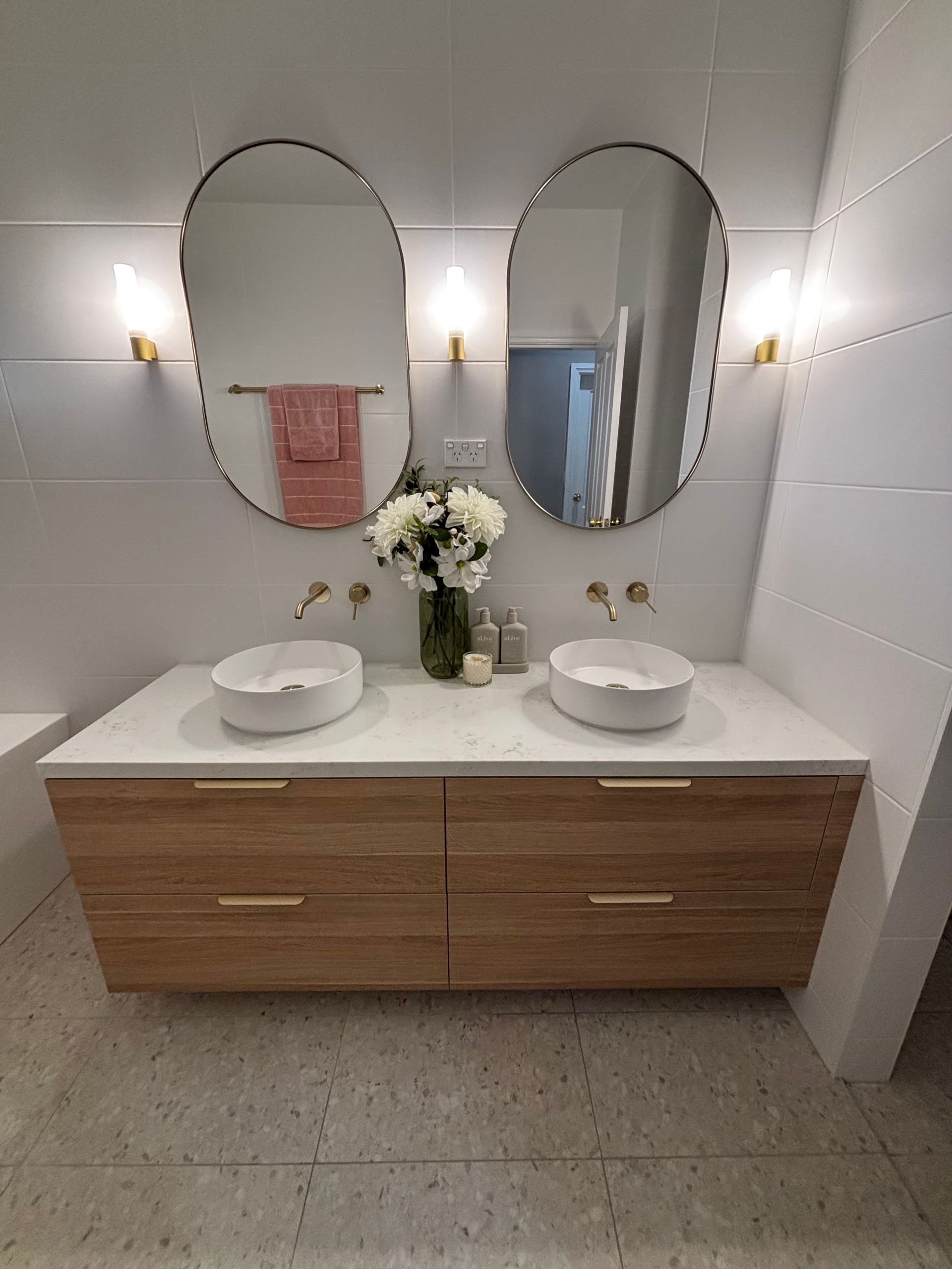 Modern Bathroom Vanity With Two Oval Mirrors, White Sinks, Wooden Cabinet — JAJ Plumbing in Mount Austin, NSW