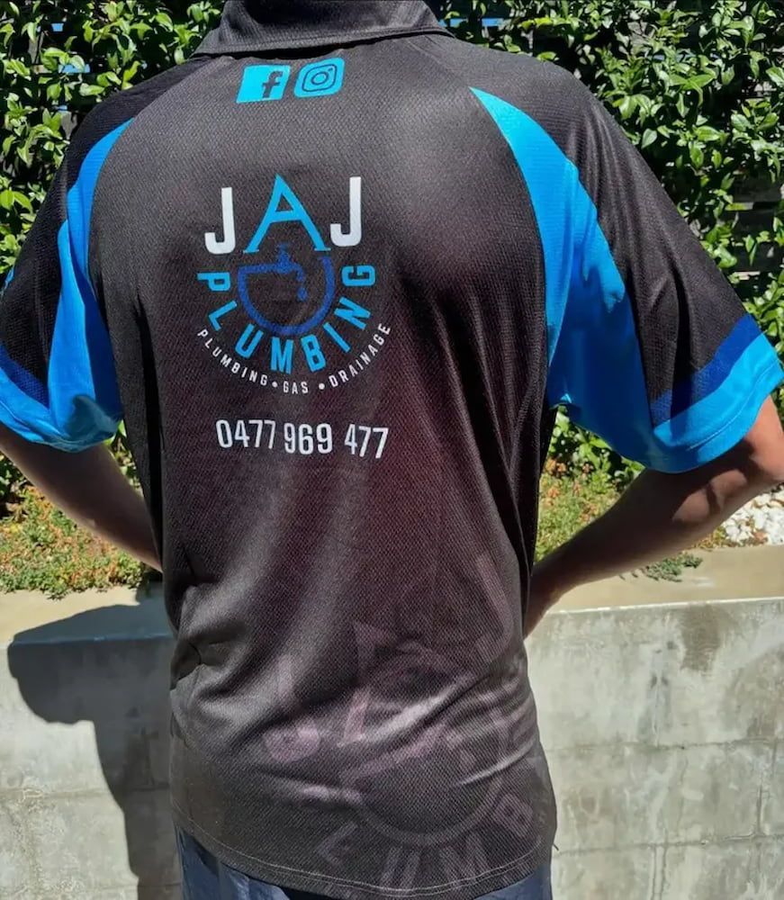 Person Wearing a Black and Blue JAJ Plumbing T-shirt, Seen From the Back Outdoors — JAJ Plumbing in Mount Austin, NSW