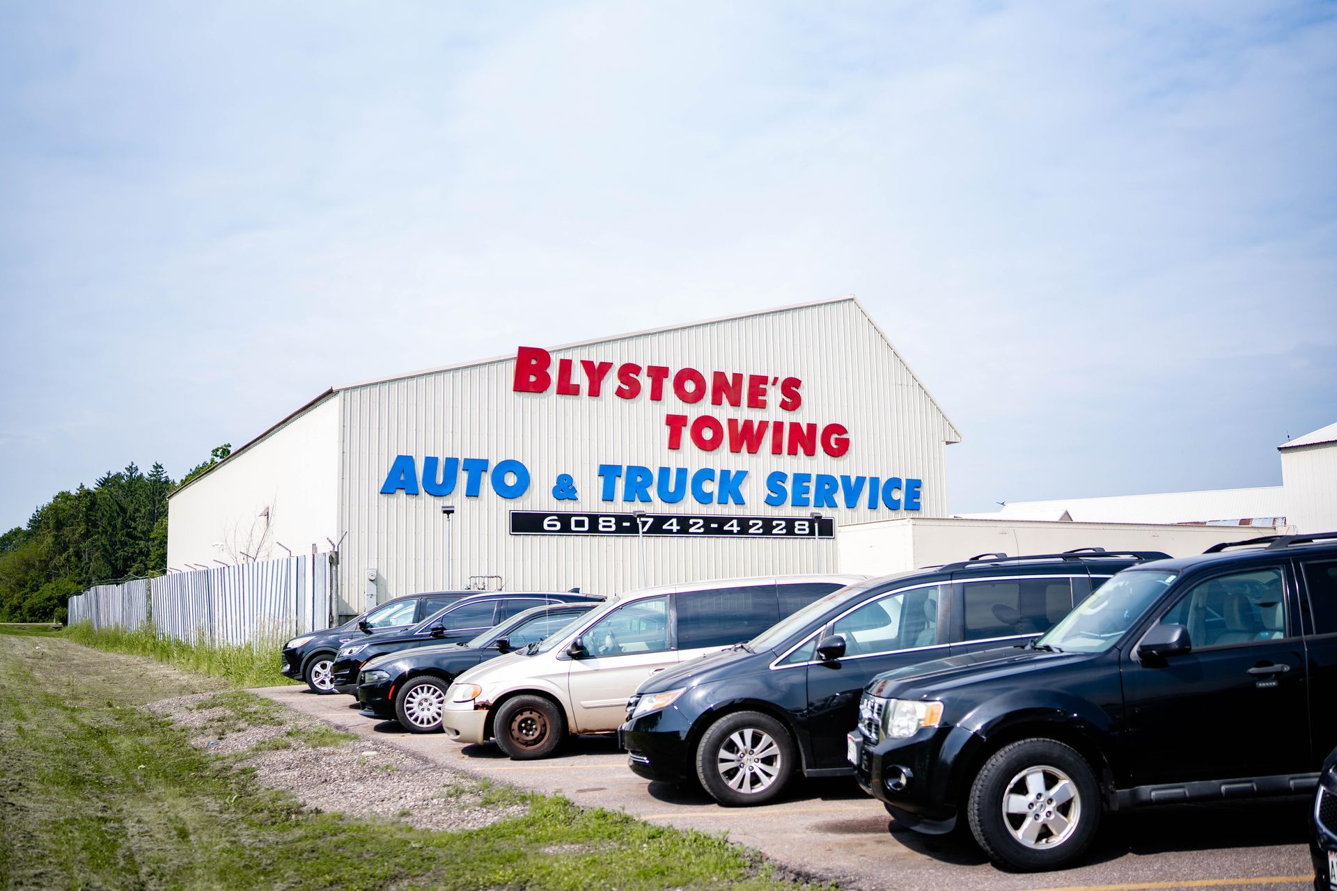 Blystone's Towing building with parked cars in front. White building with red and blue lettering.