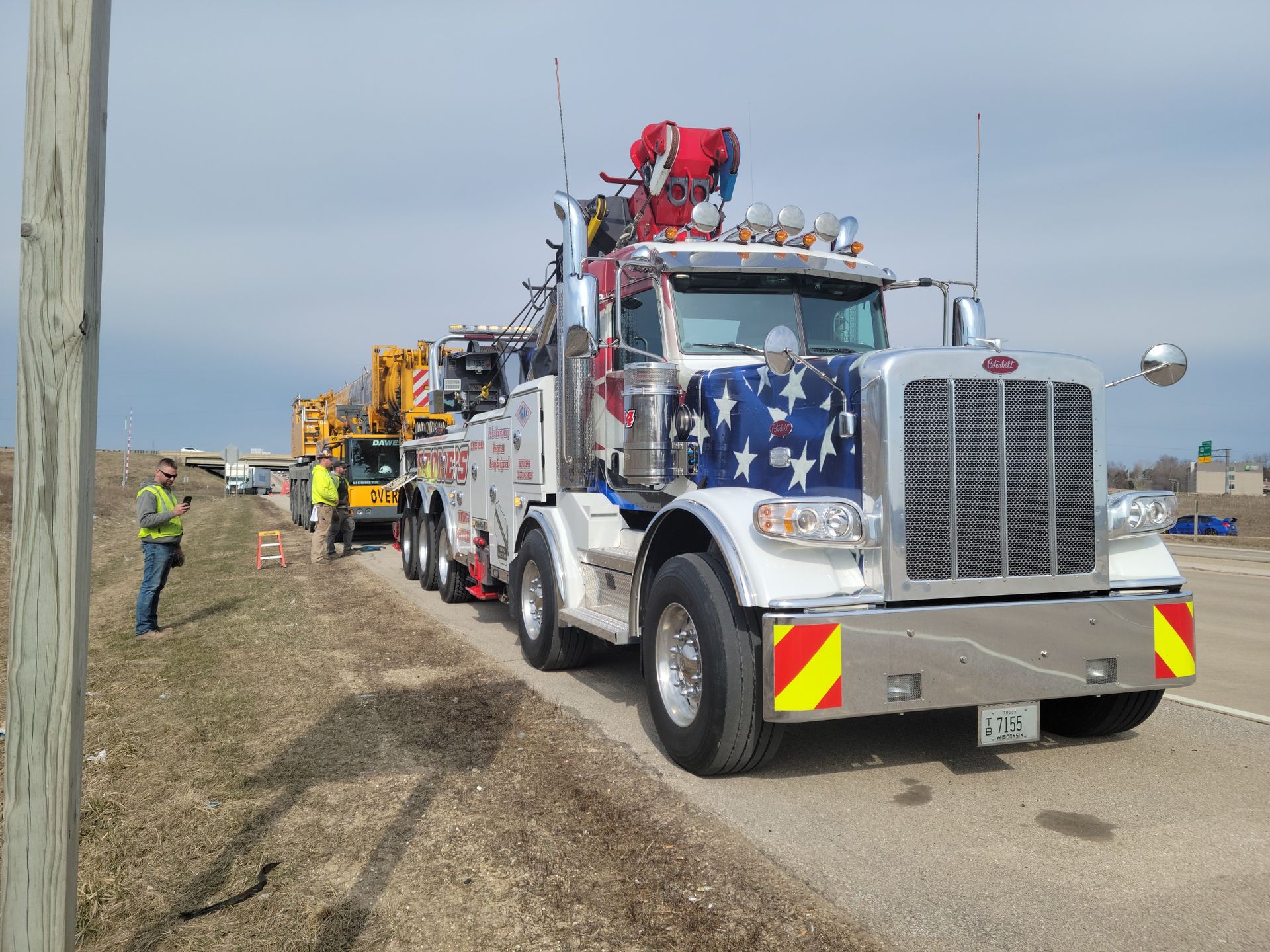 Line of decorated utility trucks parked on a roadside, with a worker standing nearby under a cloudy sky