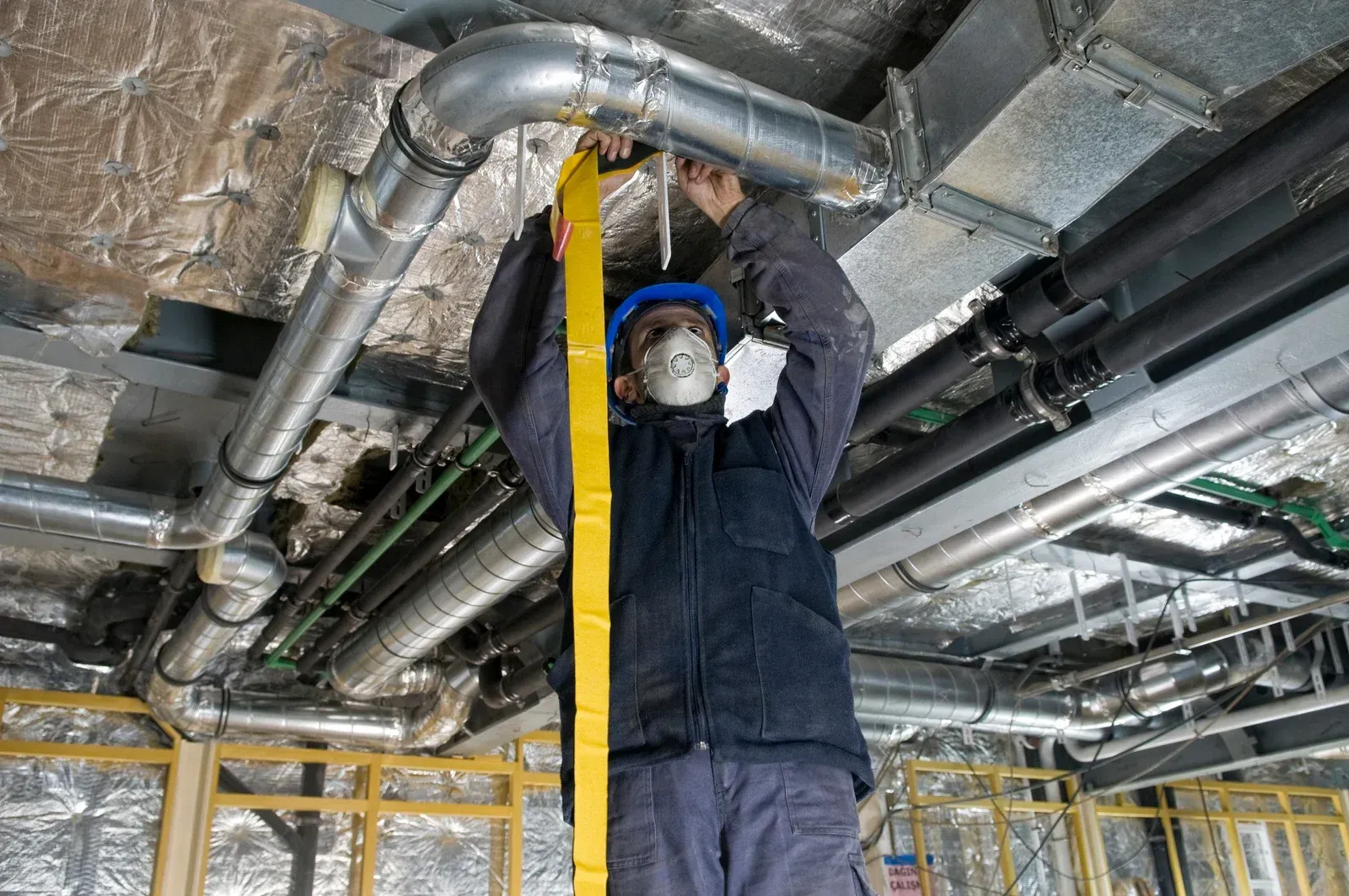 A man is measuring a pipe with a tape measure.