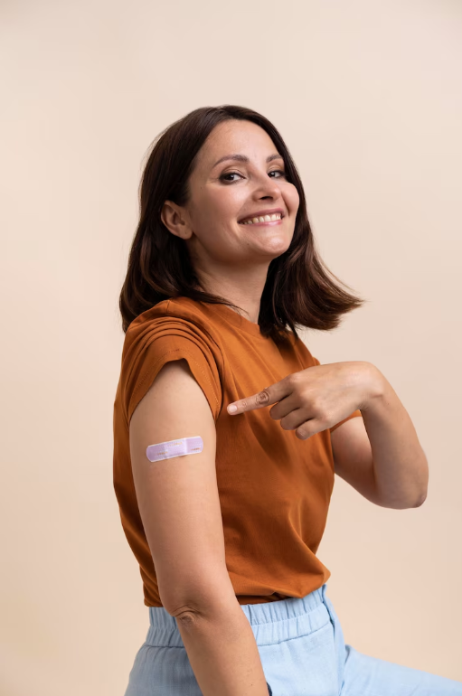 Una mujer señala su brazo con un vendaje.