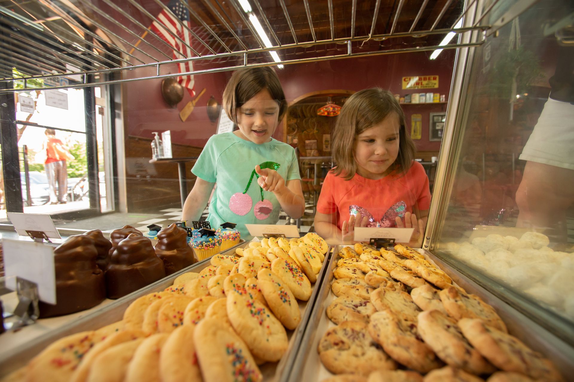 Two children look at pastries in a bakery display case.