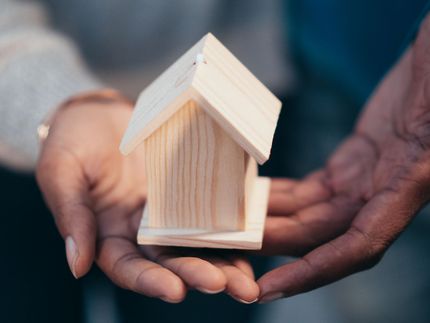 Hands gently holding a small wooden house model