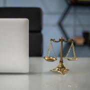 Small gold scales of justice beside a silver laptop on a desk