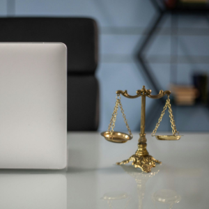 Small gold scales of justice beside a silver laptop on a desk