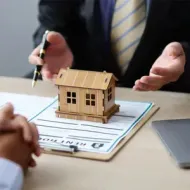 Handshake over tabletop architectural model between two people in an office meeting