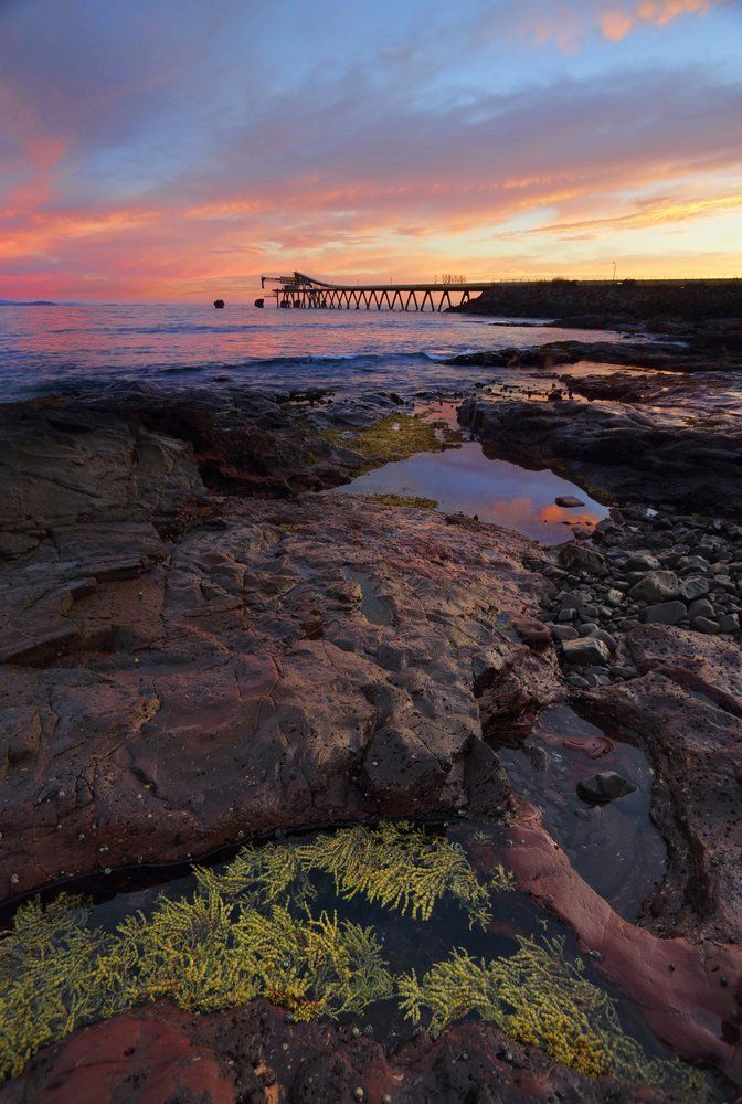 A Sunset Over a Rocky Beach With a Pier in the Distance — South Coast Clothes Lines in Shellharbour, NSW
