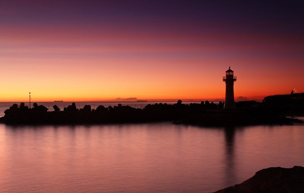 A Lighthouse is Silhouetted Against a Sunset — South Coast Clothes Lines in Wollongong, NSW