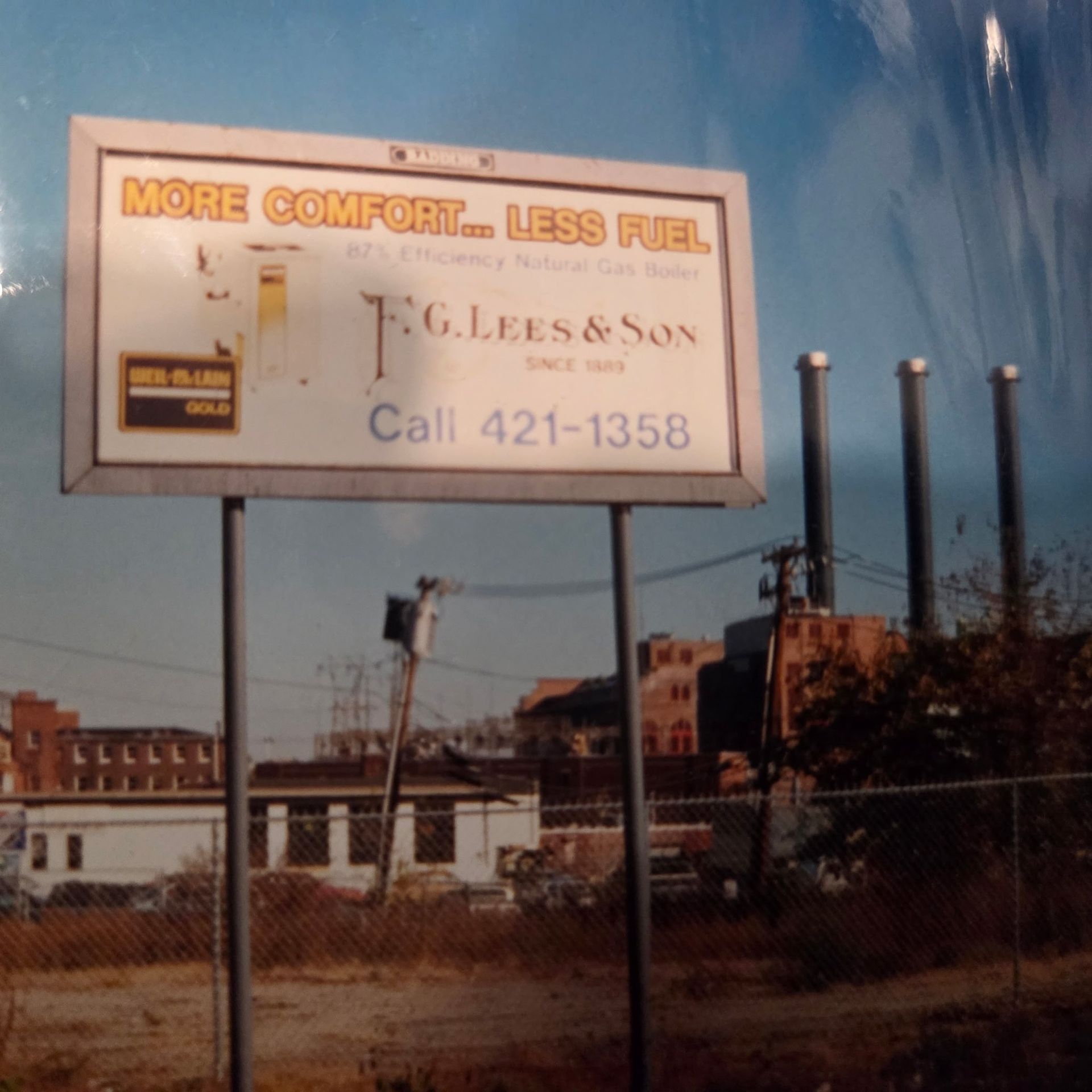 Faded roadside billboard for T. G. Lee & Son with “More comfort... less fuel” and phone number 421-1358.