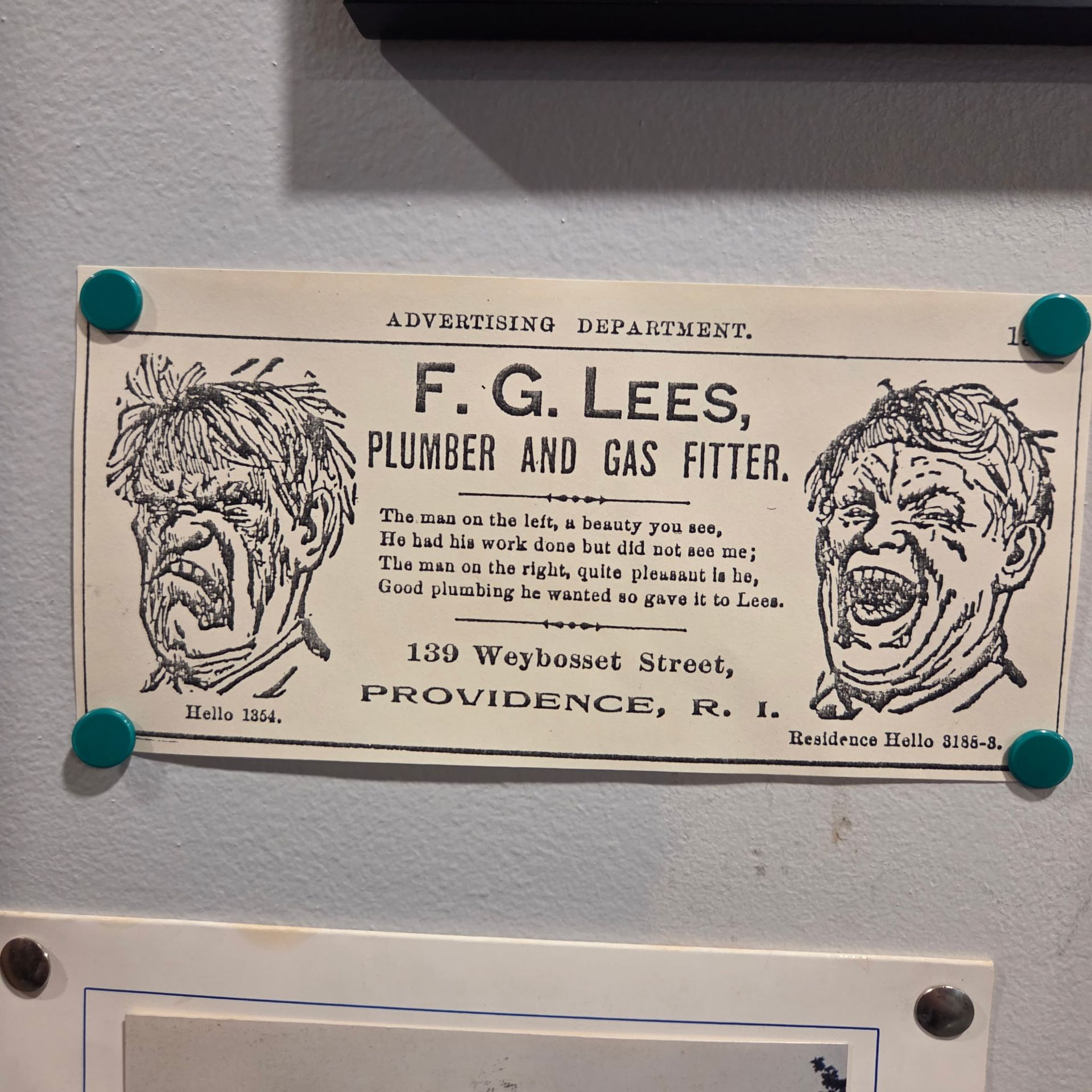 Vintage F. G. Lees plumber and gas fitter ad card pinned to a wall with two cartoon faces.