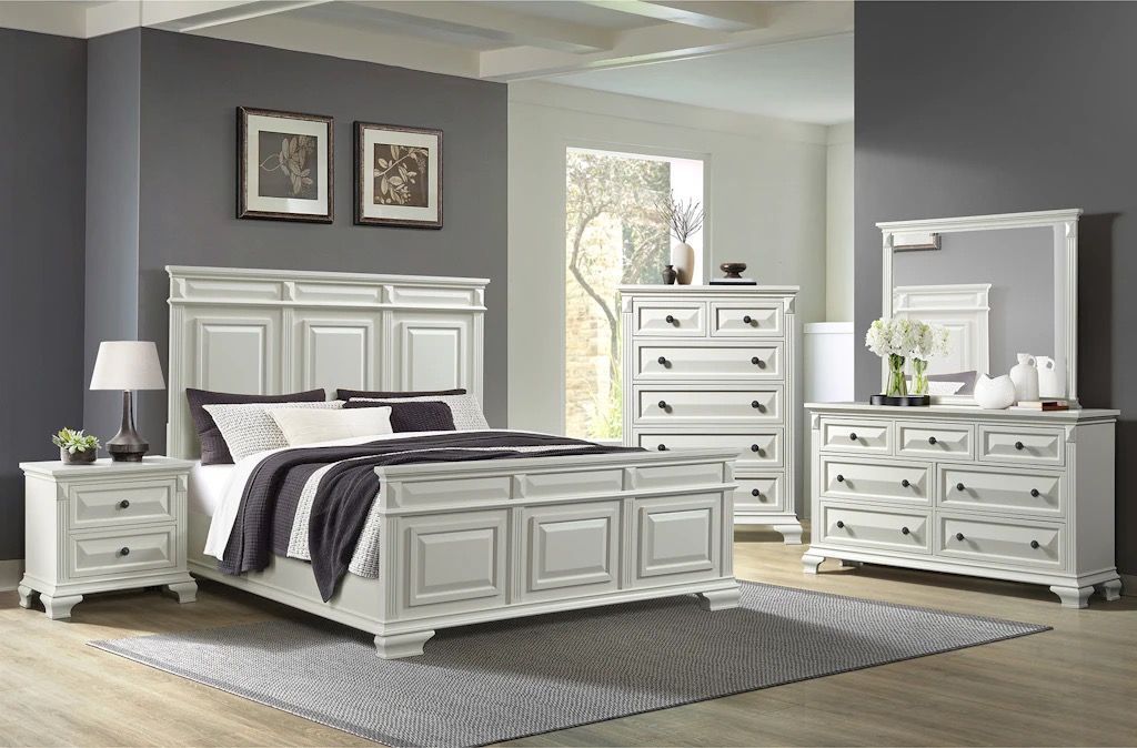 A bedroom with a bed , dresser , nightstand and mirror.