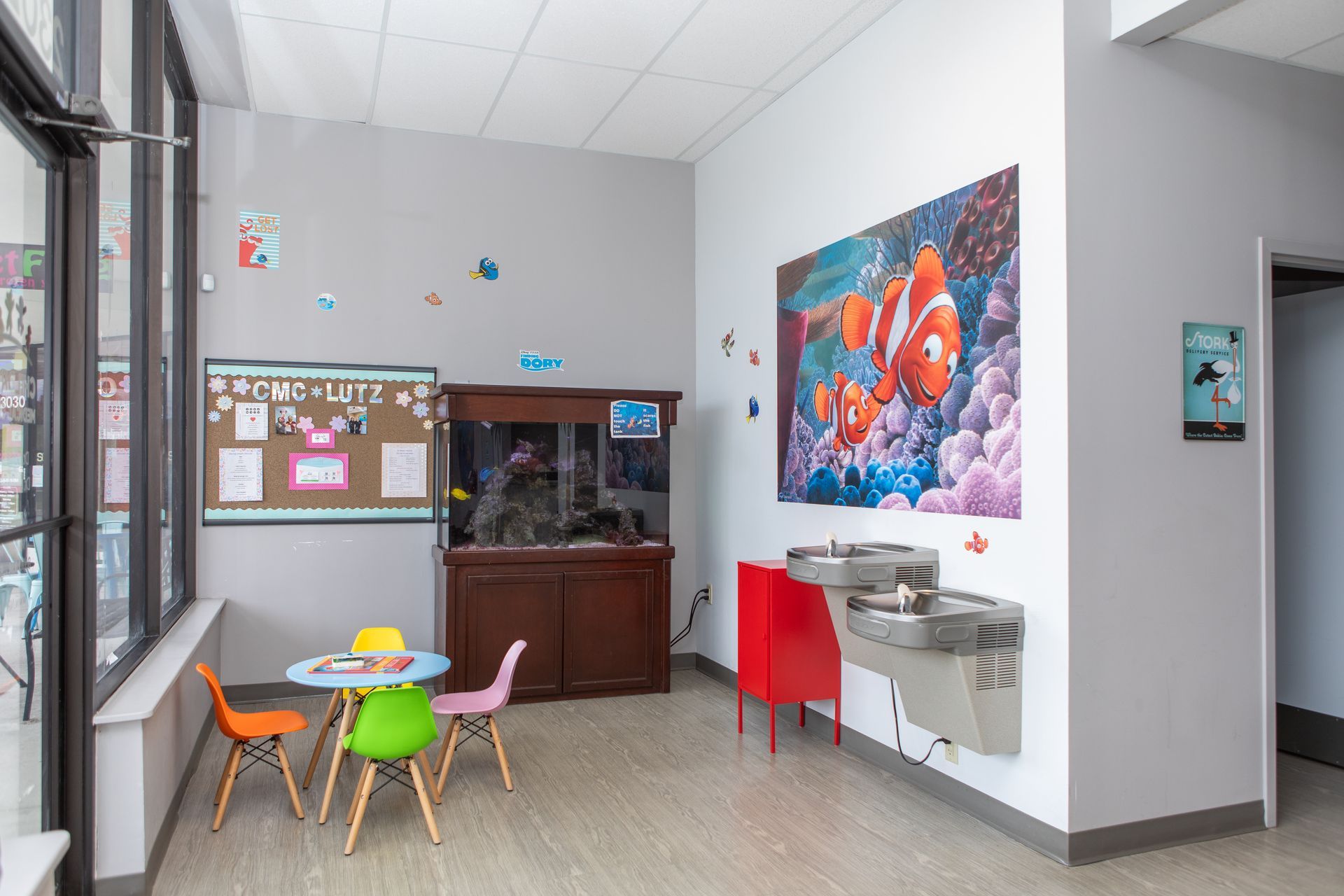 A room with a table and chairs and a fish tank on the wall.