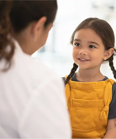 A little girl is talking to a doctor in a hospital.