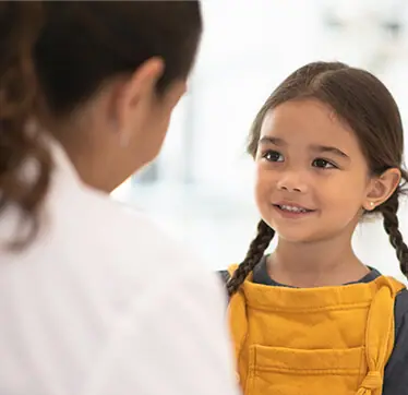 A pediatrician at Children's Medical Center is talking to a young girl
