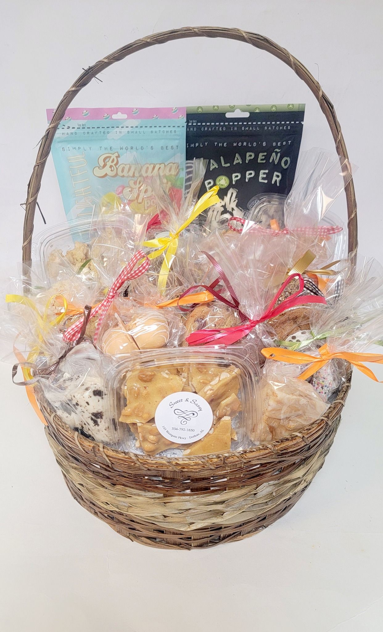 Gift basket with snacks, wrapped in cellophane, with a wicker handle.