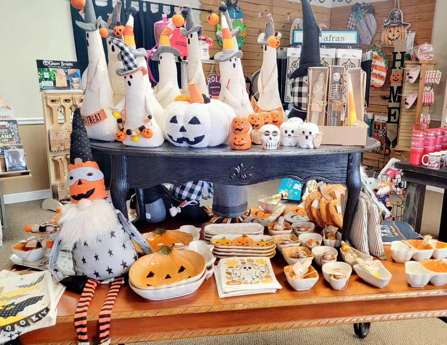 Halloween decorations on a table in a store: ghosts, pumpkins, skulls, and treats.