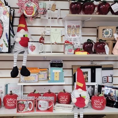 Shelves stocked with teacher-themed gifts: apple decorations, mugs, gnomes, and signs.